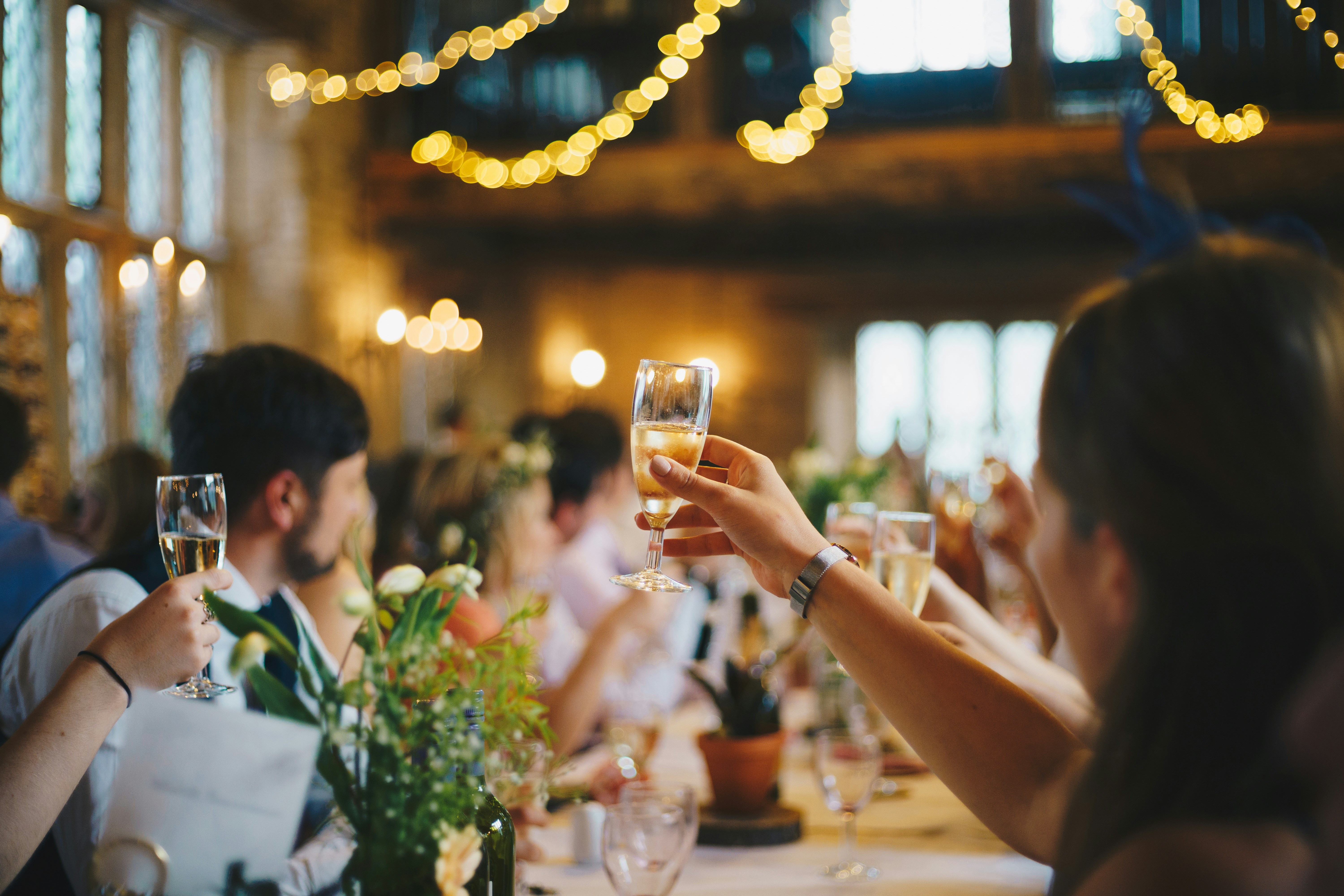People celebrating at an elegant event with champagne glasses and string lights